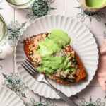 Lemony ground turkey stuffed sweet potato on a plate topped with a herby yoghurt sauce.