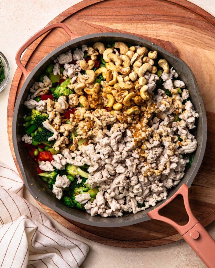 Cooked ground chicken added to the pan of stir fried veggies as well as sauce and cashews.