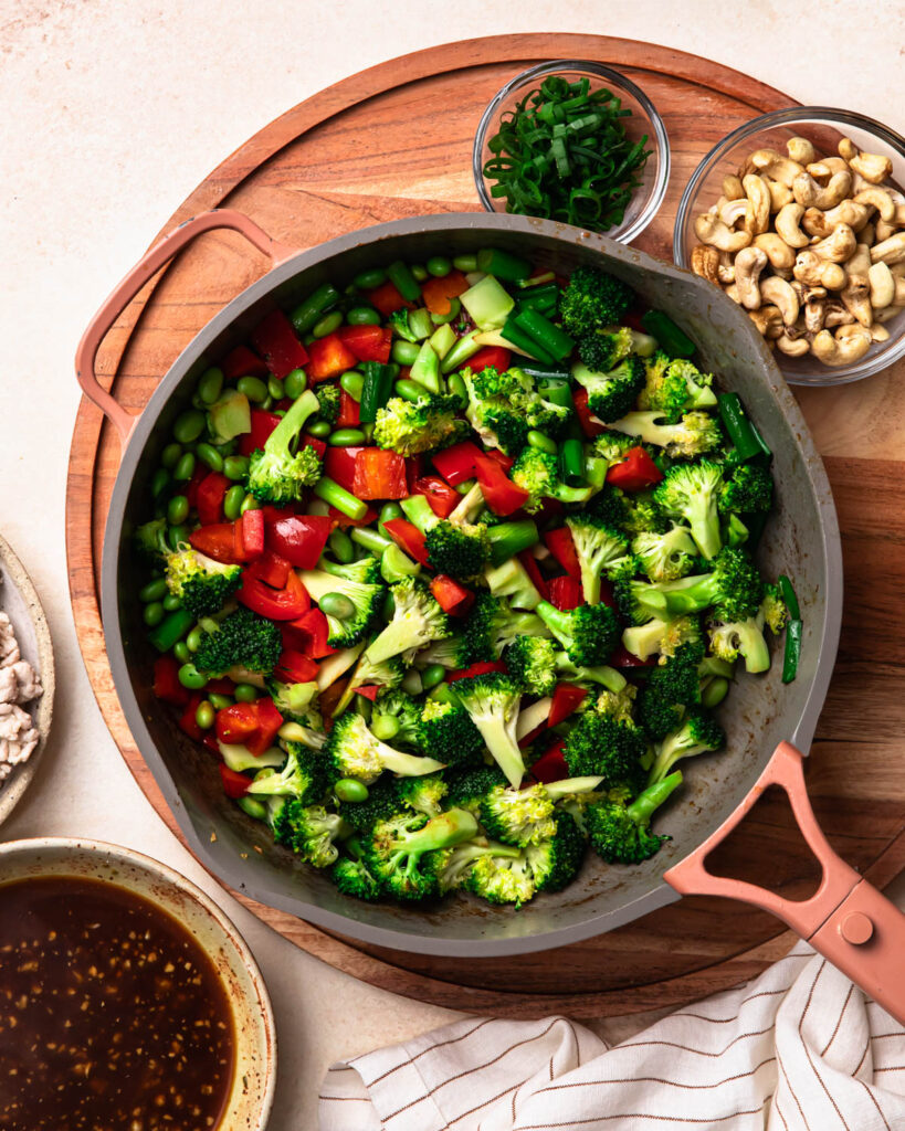 Veggies stir frying in a pan to make ground chicken stir fry.