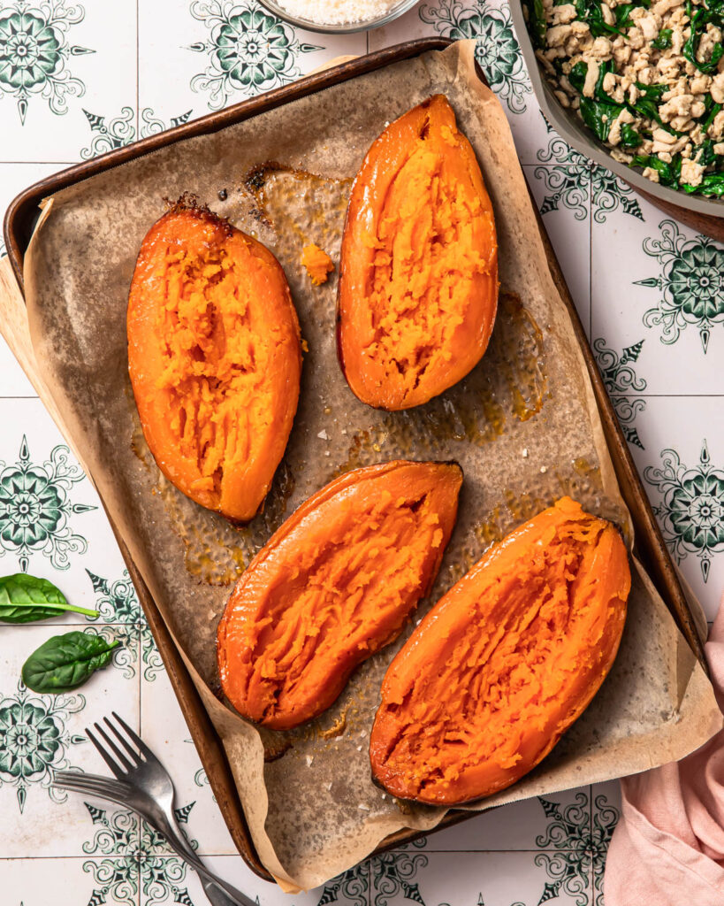 Roasted sweet potato halves with the flesh mashed to create a well.