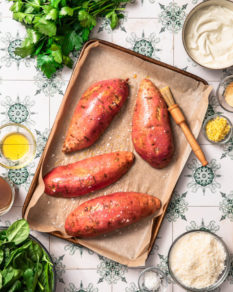 Sweet potatoes cut into halves and placed cut side down on a large baking tray.