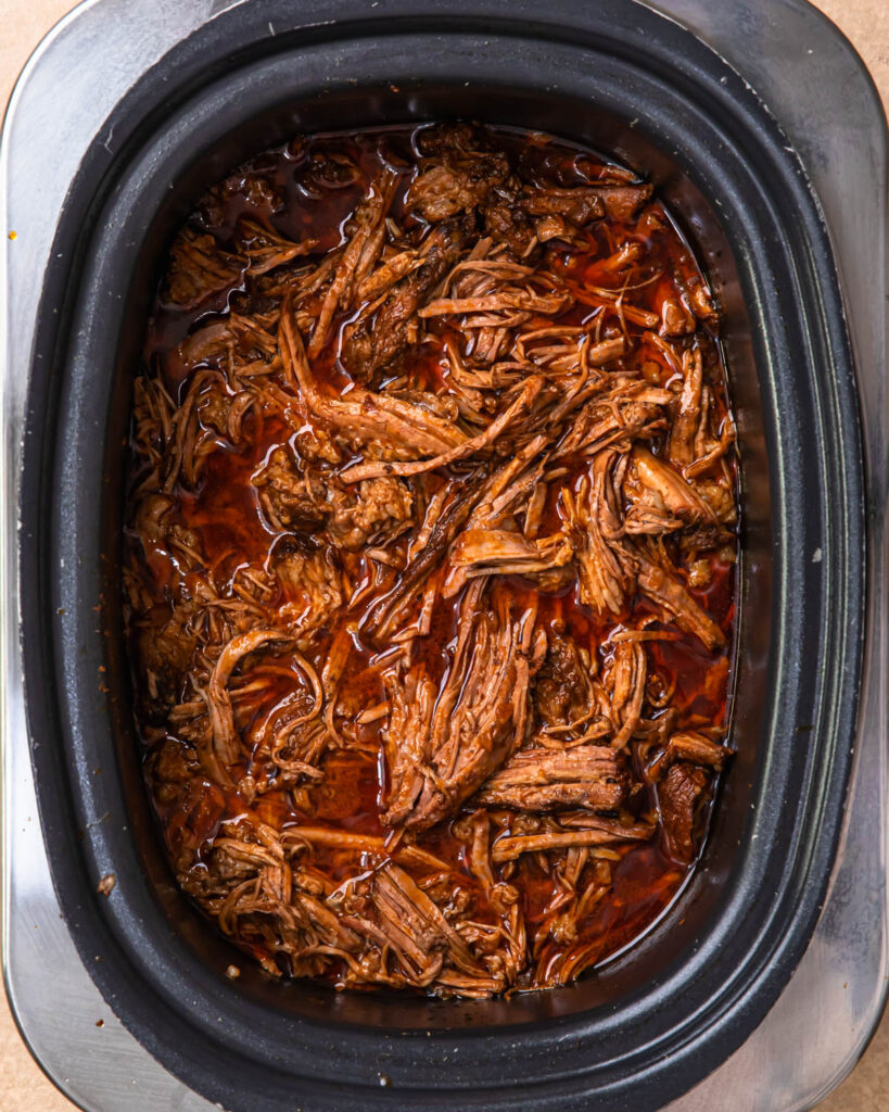 Shredded beef brisket in a slow cooker.
