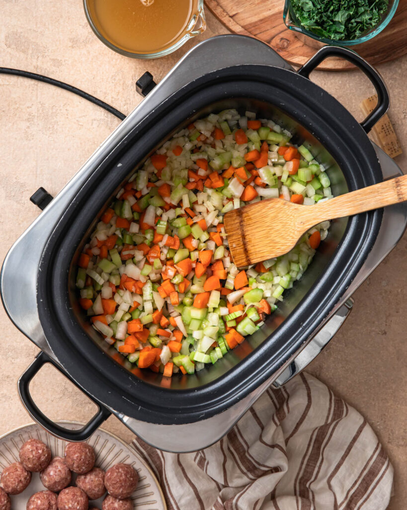 Carrots, onion and celery sautéing as the base for slow cooker meatball soup.