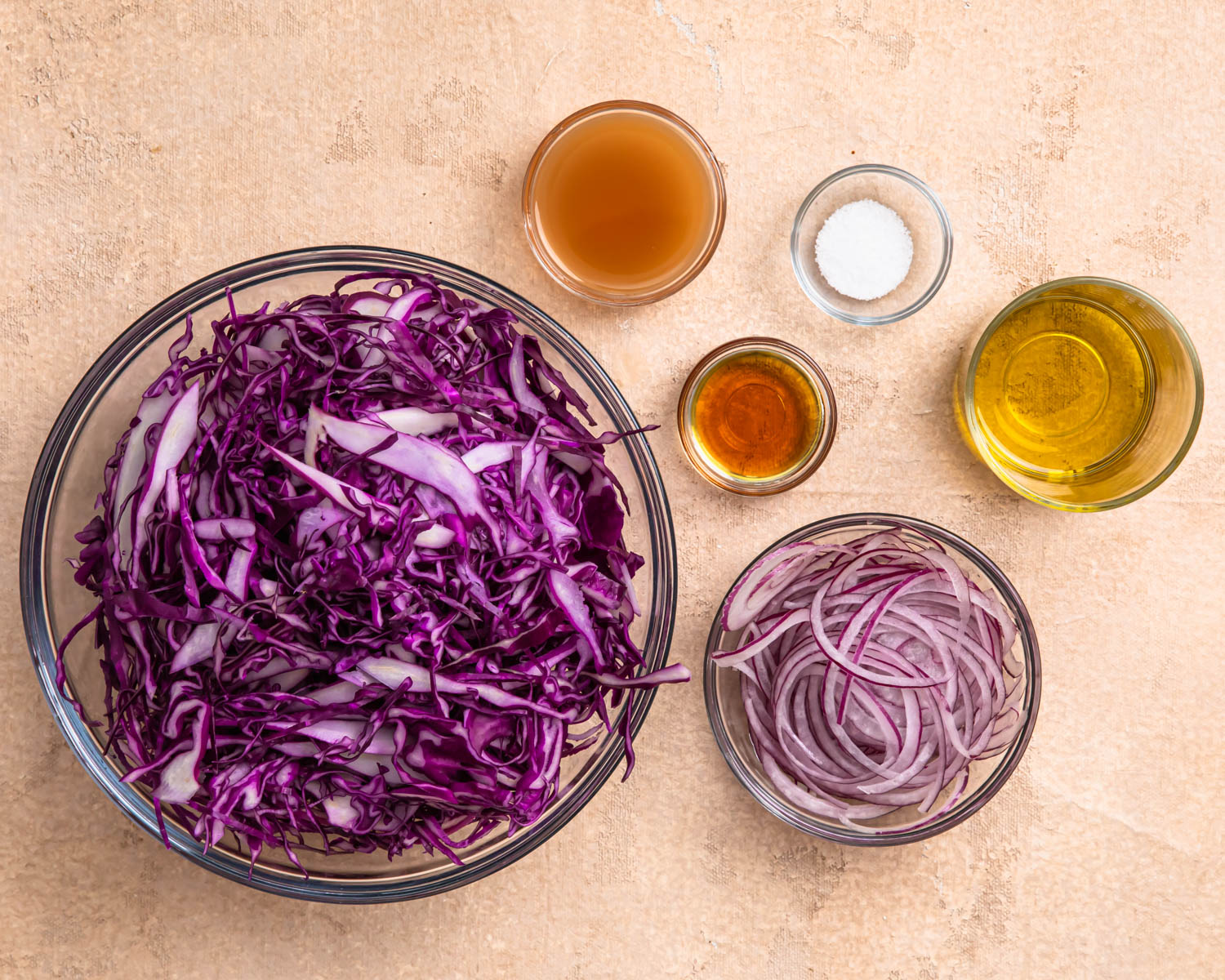 Ingredients for cabbage slaw laid out in individual bowls.