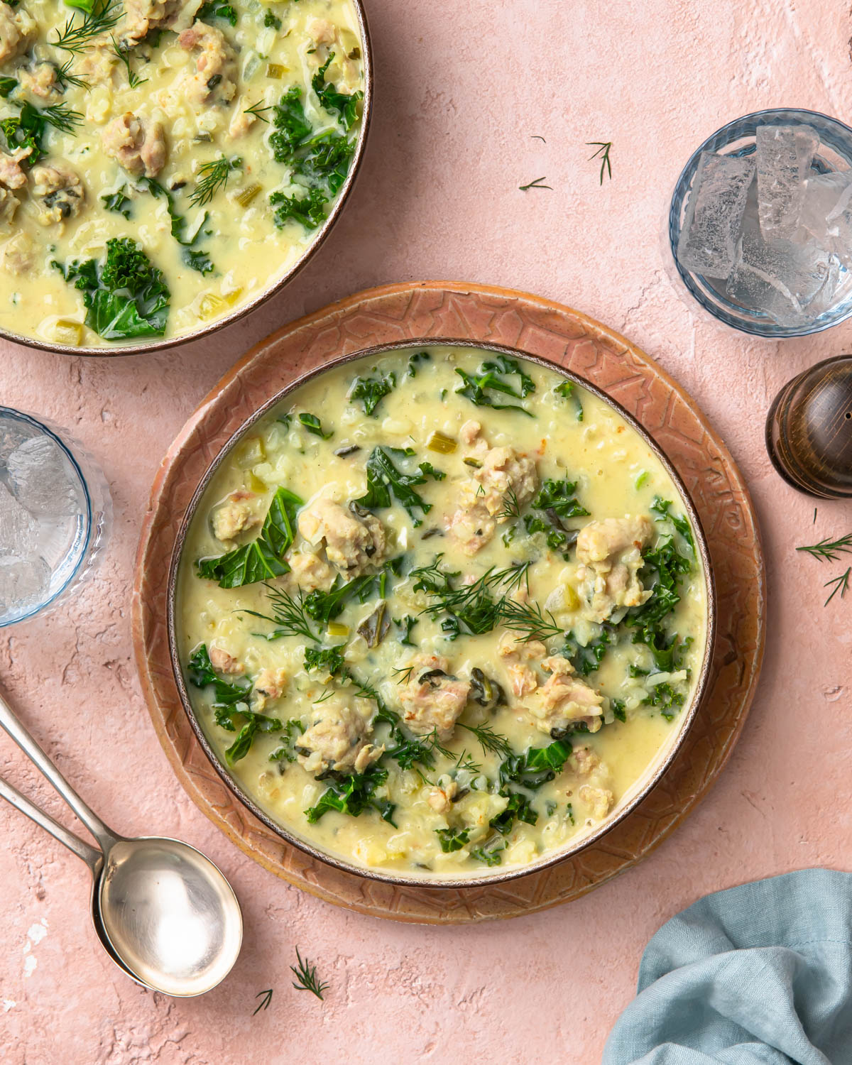 Two bowls of chicken lemon rice soup, both garnished with dill.