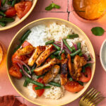 Overhead shot of a harissa chicken bowl with rice, sauce, veggies and chicken.