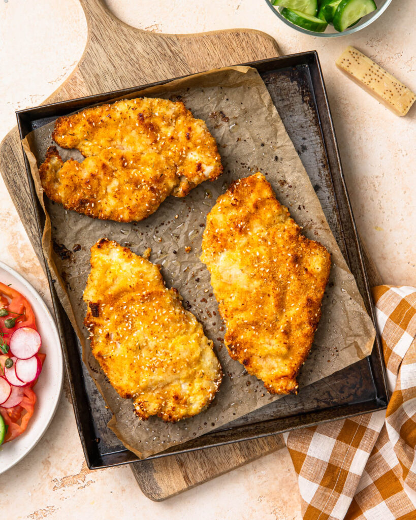 Baked parmesan breaded chicken on a sheet pan.