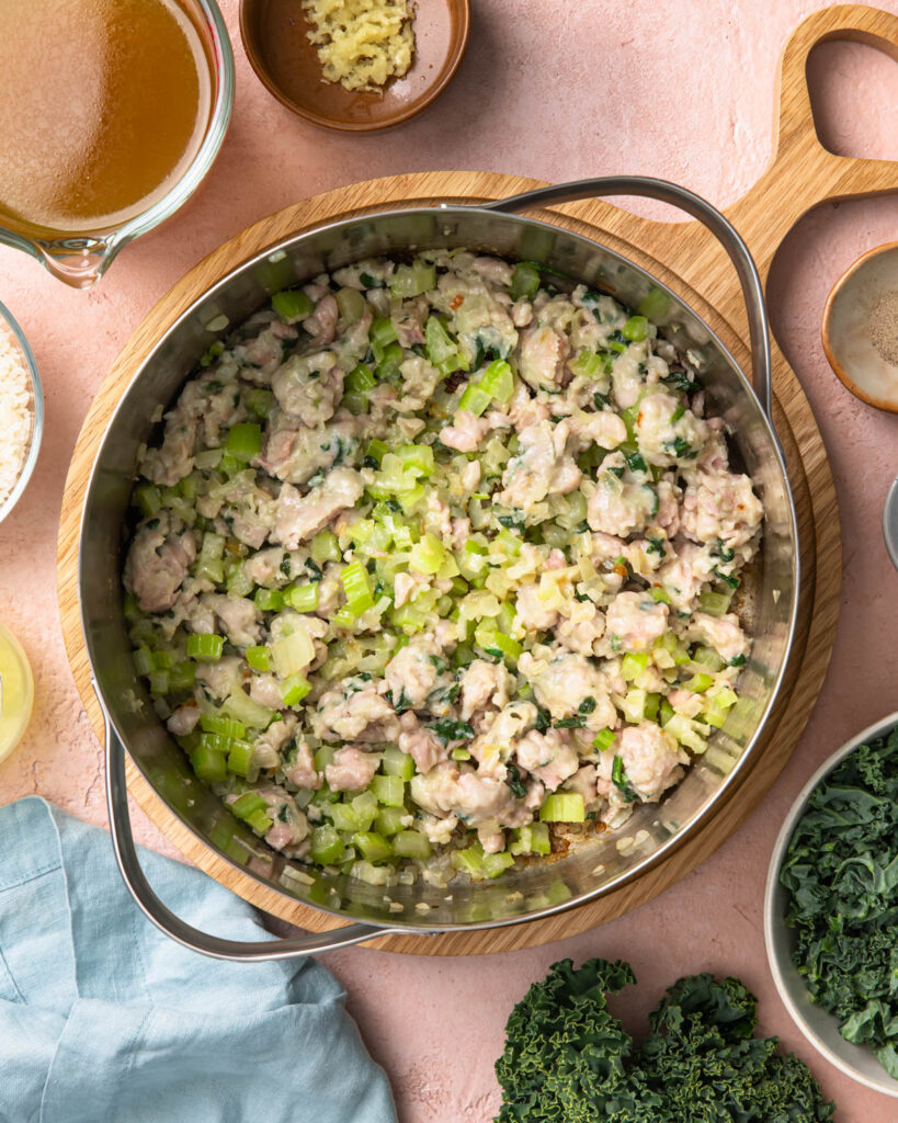 Sausage and vegetables cooking in a large soup pot.