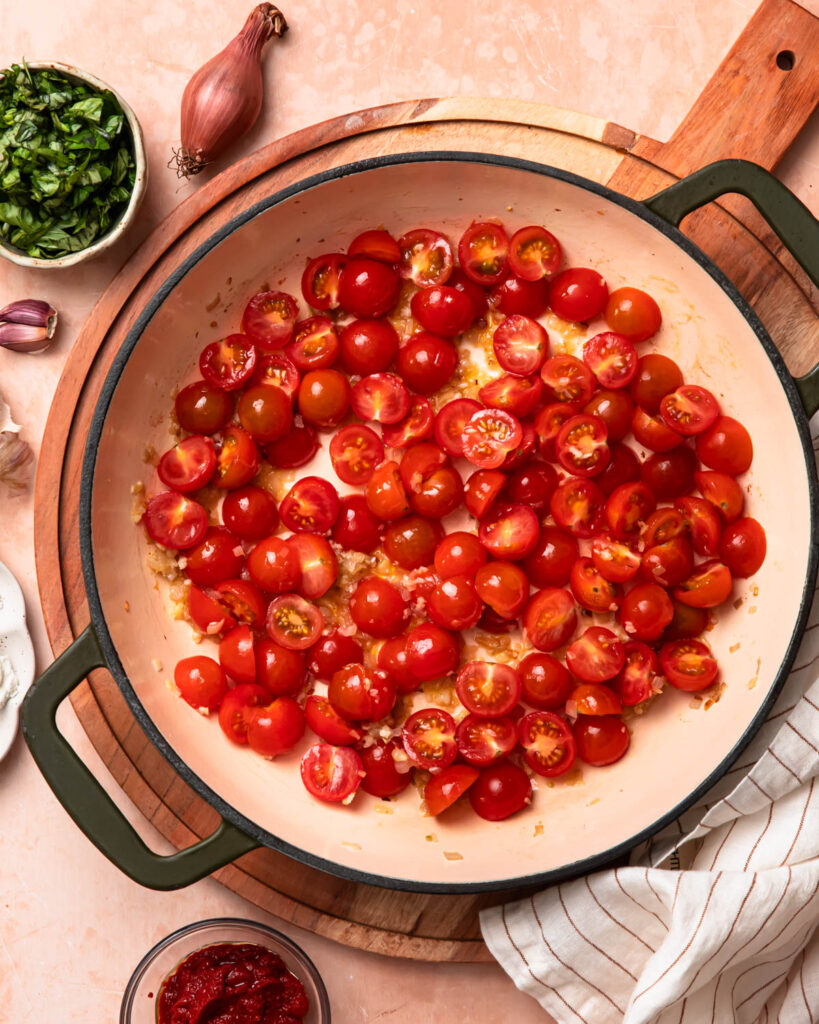 Diced cherry tomatoes cooking in a skillet.