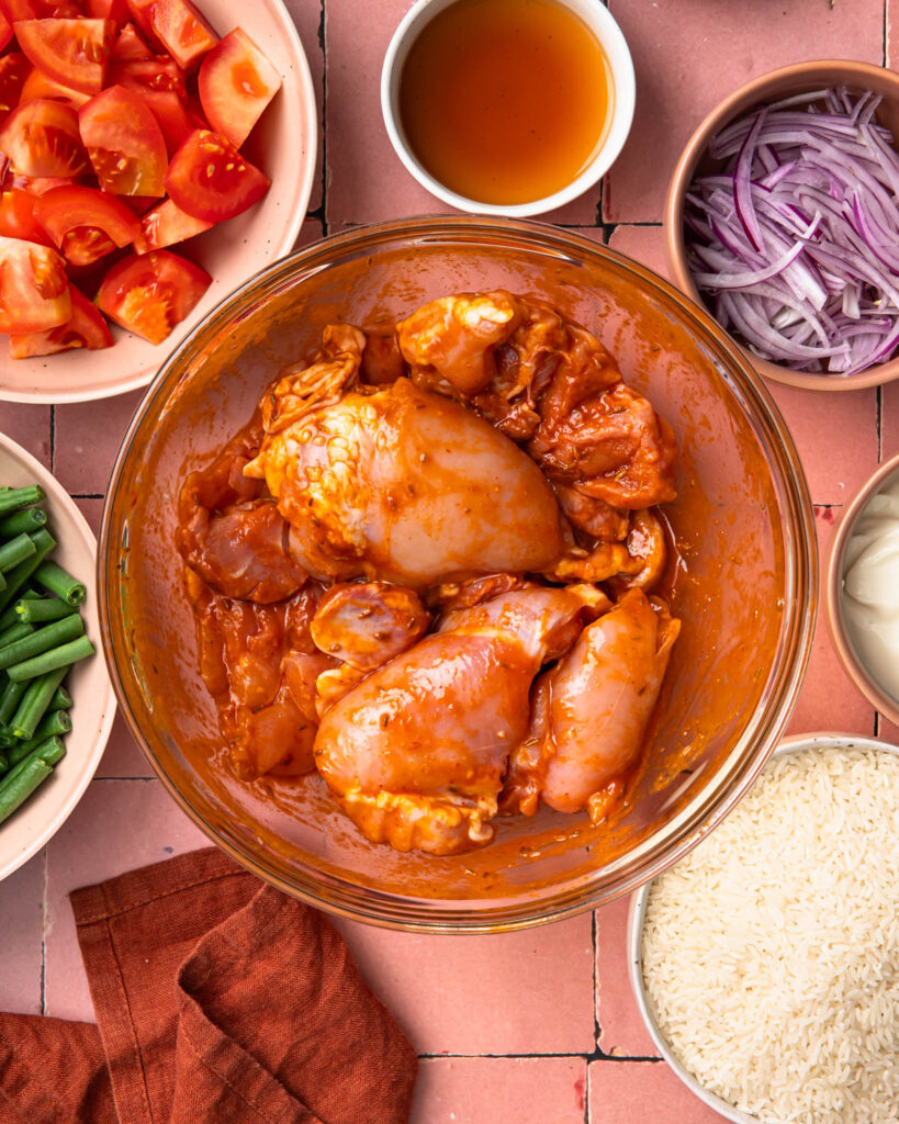 Chicken thighs in harissa marinade in a bowl.