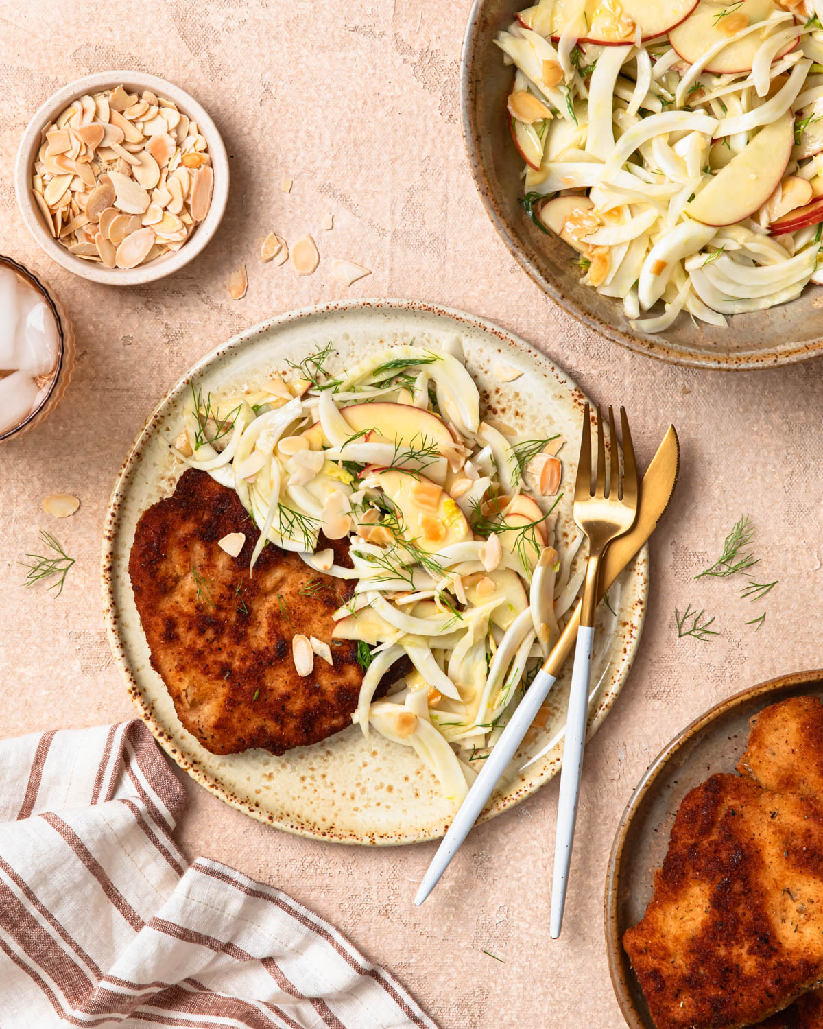 Top down photo of crumbed pork schnitzel and apple and fennel slaw on a plate.