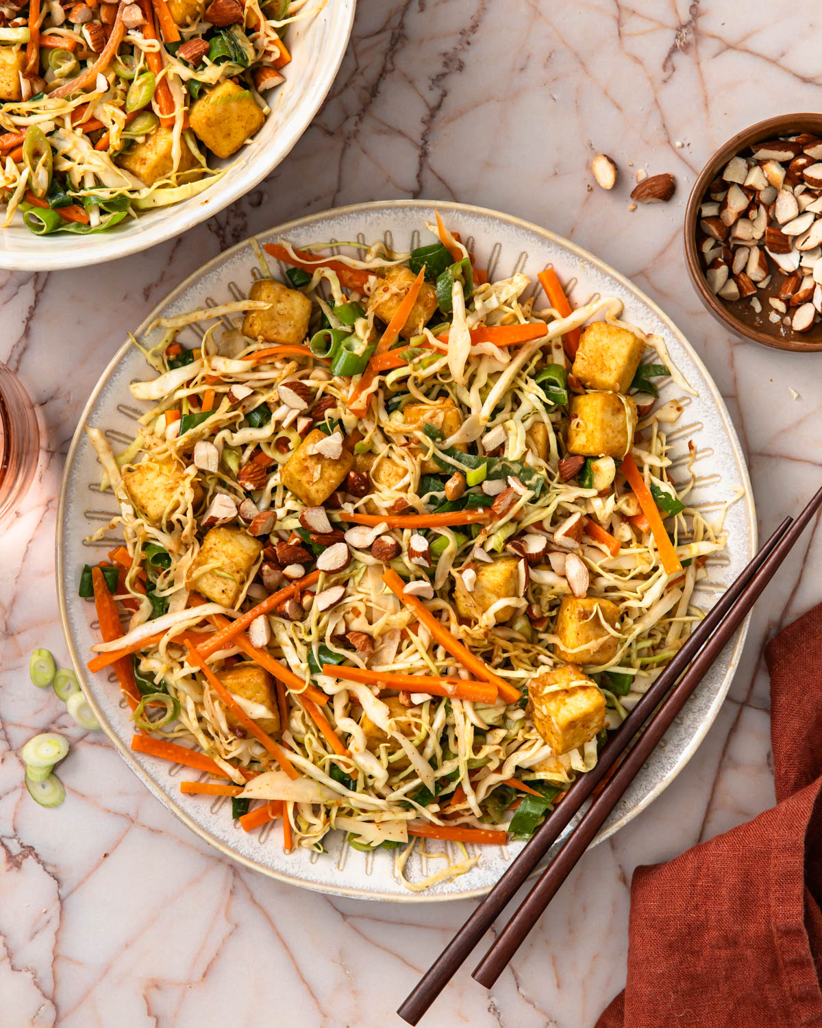 Large bowl full of a crunchy tofu salad with chopsticks on the side of the bowl.