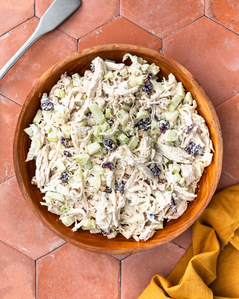 Mixed up cranberry chicken walnut salad in a large wooden bowl.