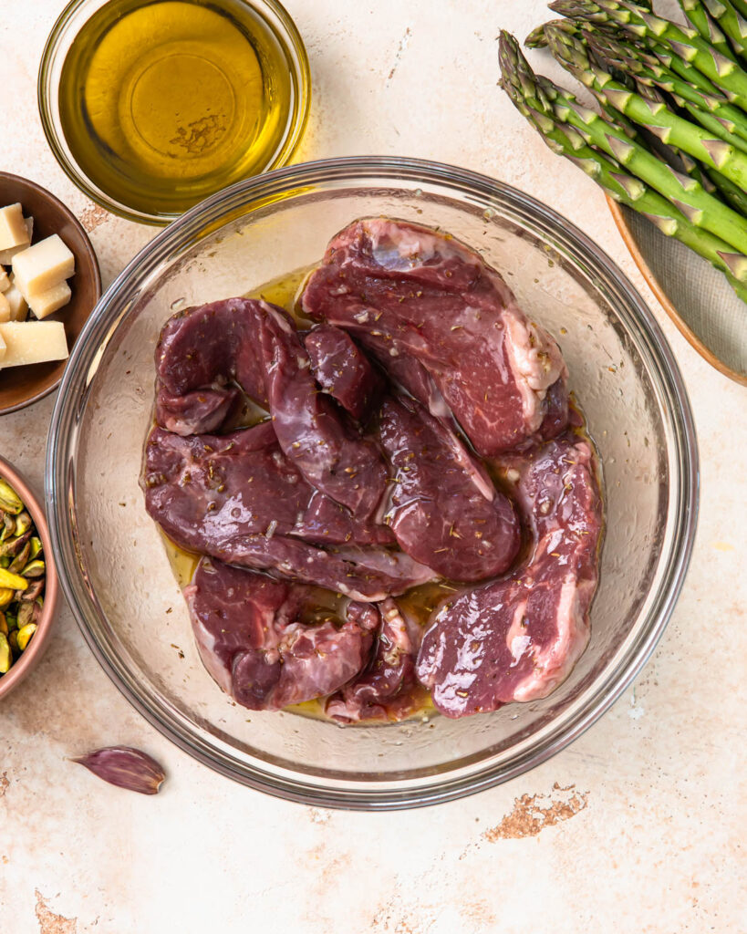 Marinating lamb fillets in a large mixing bowl.
