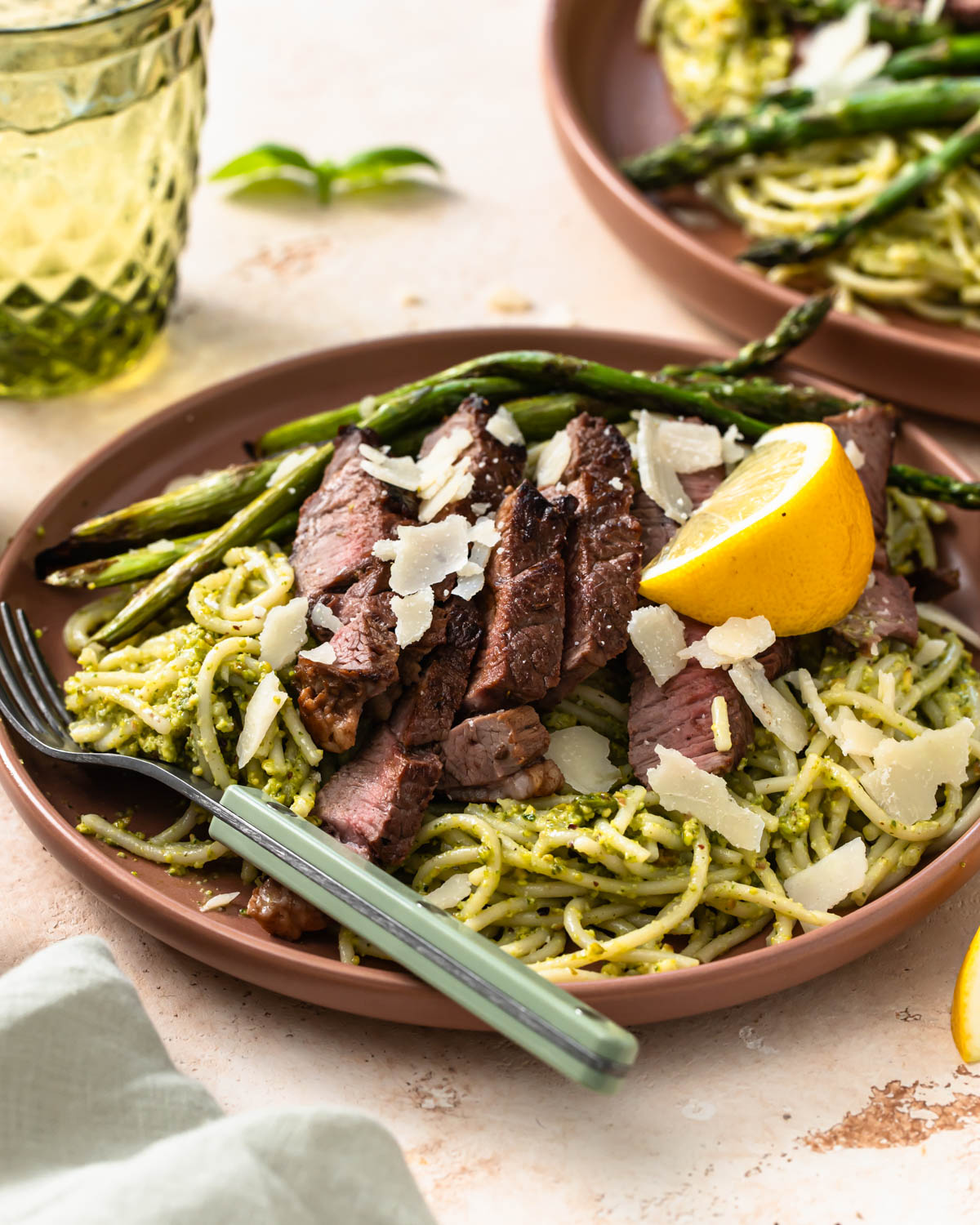 Side view of pistachio pesto pasta served with lamb rump and asparagus.