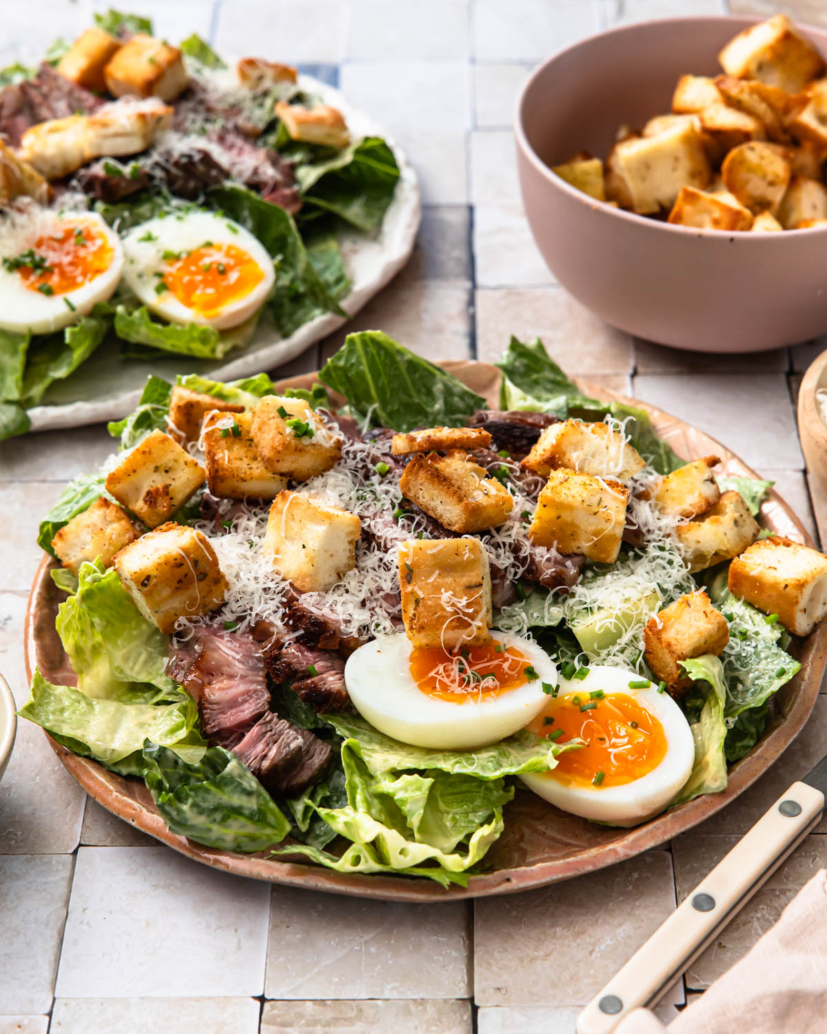 Steak caesar salad served on a plate with croutons and boiled egg.