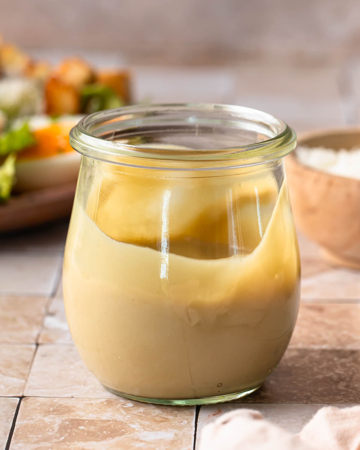 Side view of a jar of tahini caesar dressing.