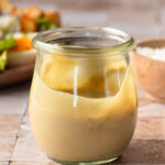 Side view of a jar of tahini caesar dressing.