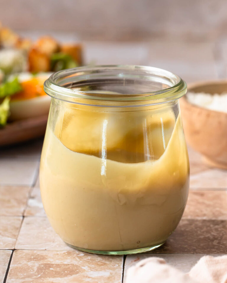 Side view of a jar of tahini caesar dressing.