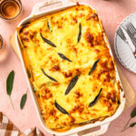 Butternut squash lasagne topped with sage leaves, in a baking dish.