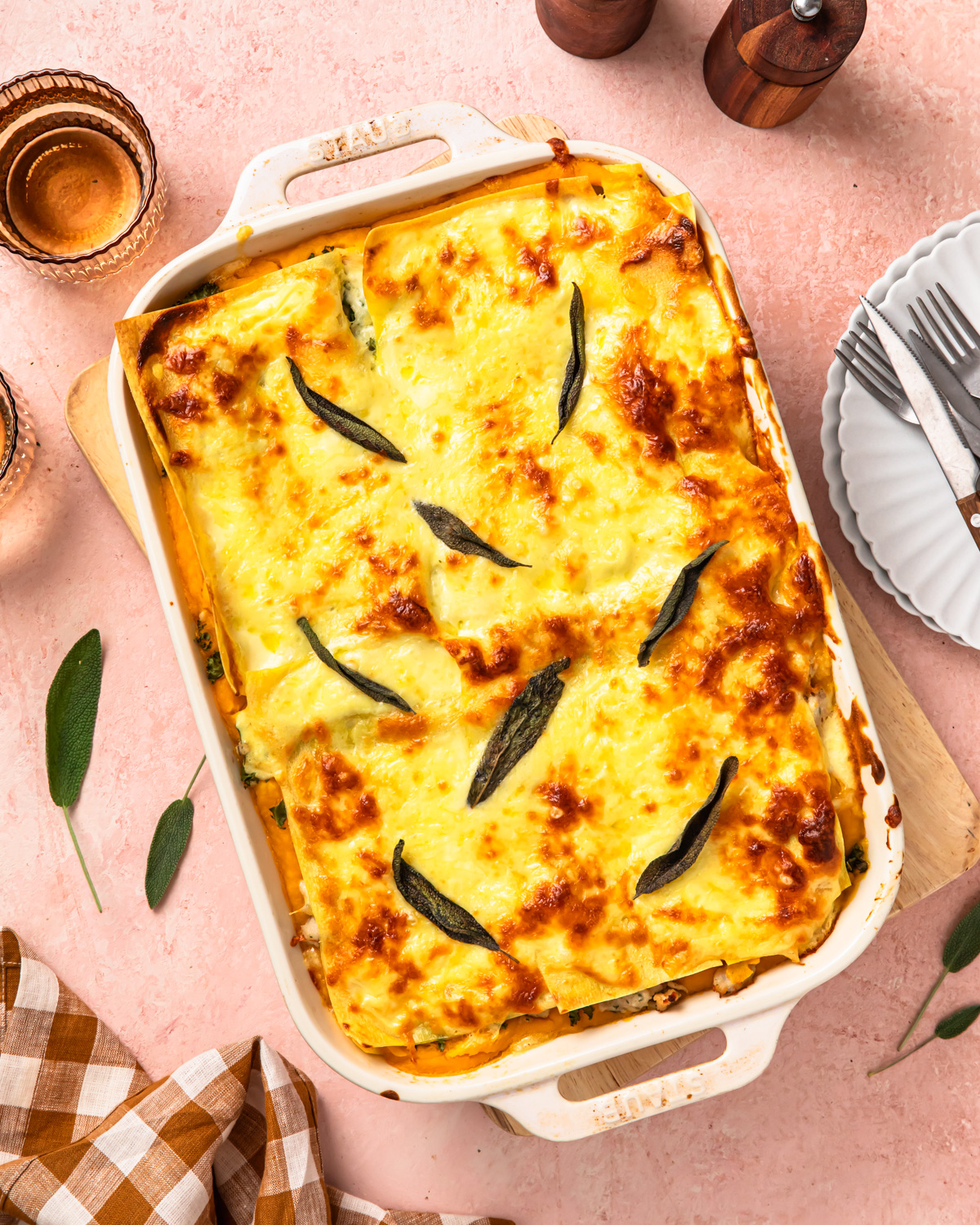 Butternut squash lasagne topped with sage leaves, in a baking dish.