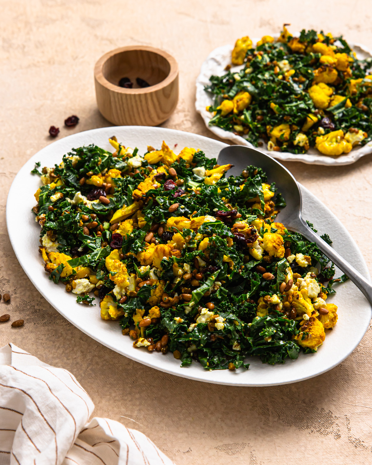 Cauliflower lentil salad on a serving dish with more on a plate behind it.