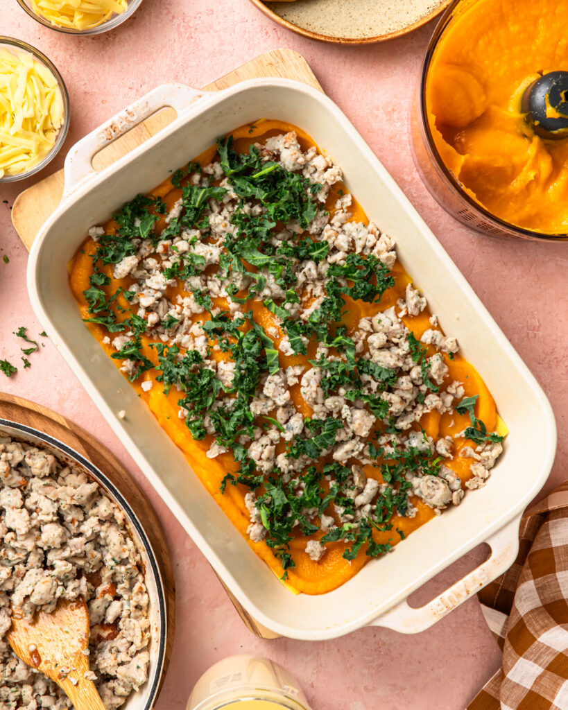 Pureed butternut squash, chicken sausage and kale layered on top of lasagne sheets in a baking dish. 