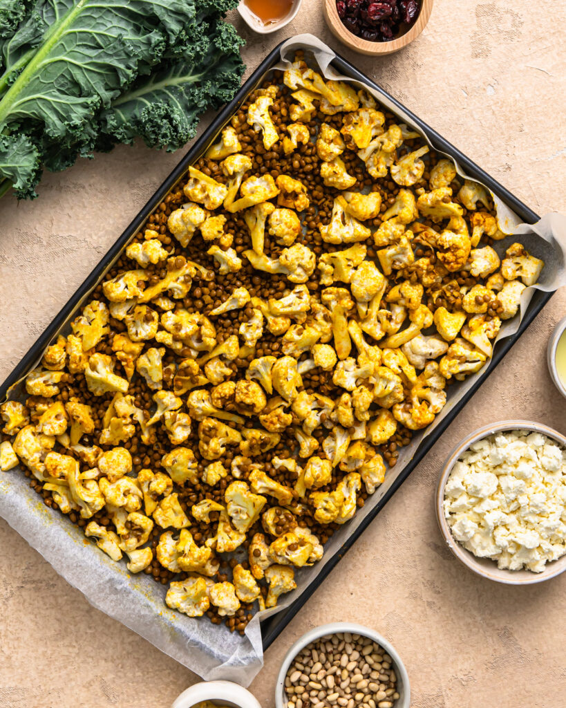 Cauliflower and lentils on a sheet pan before roasting.