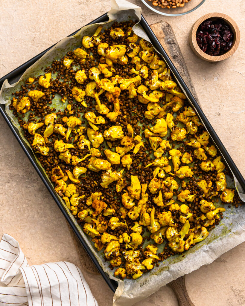 Roasted cauliflower and lentils on a parchment lined sheet pan.
