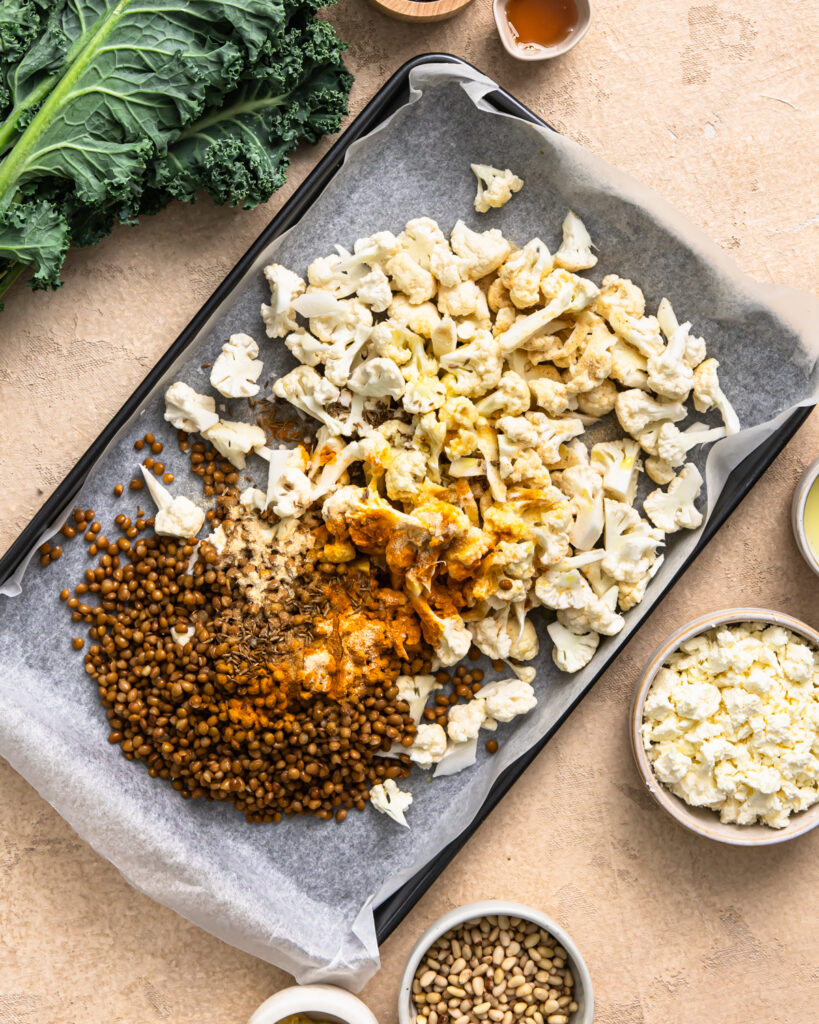 Lentils and cauliflower on a sheet pan with slices on top.