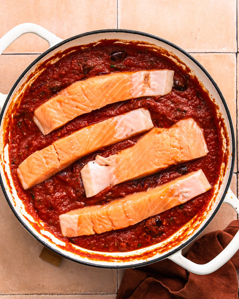 Salmon fillets added to a puttanesca sauce. 