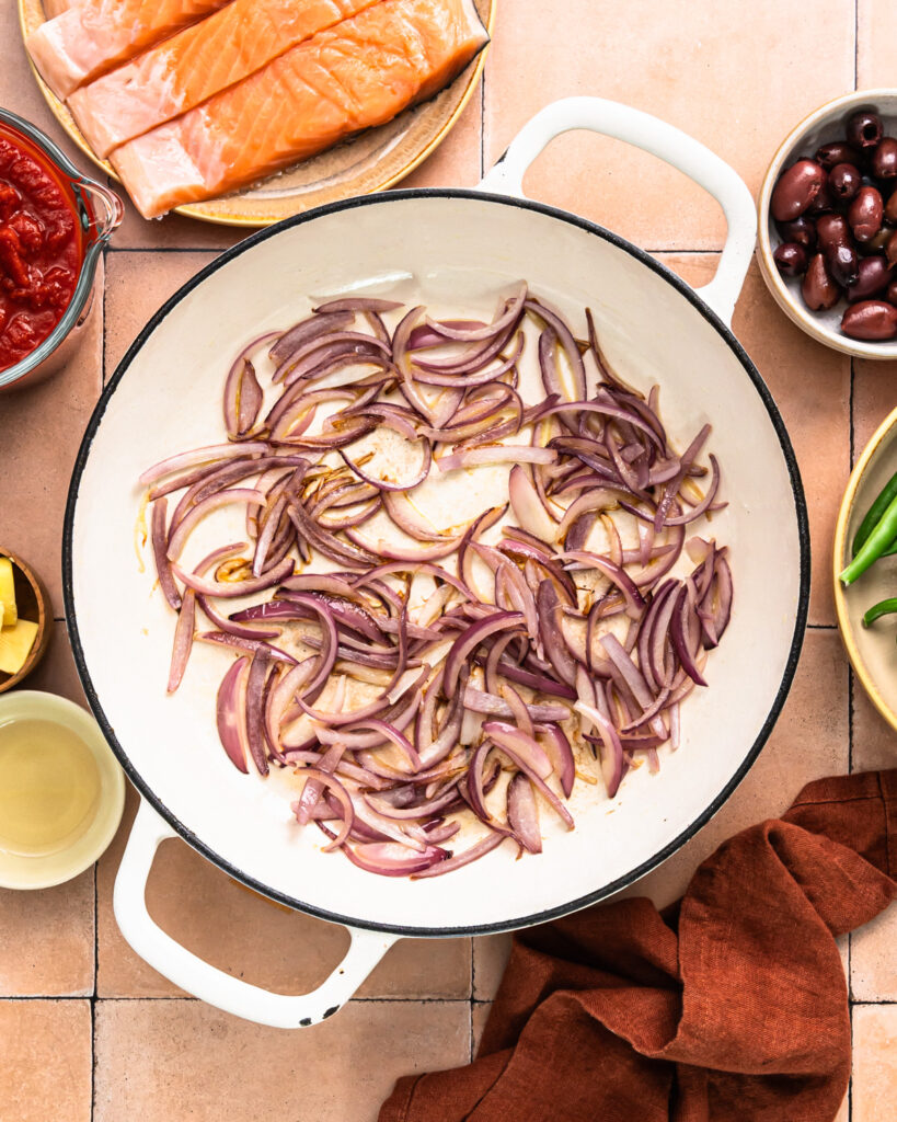 Red onions sautéing in a pan. 