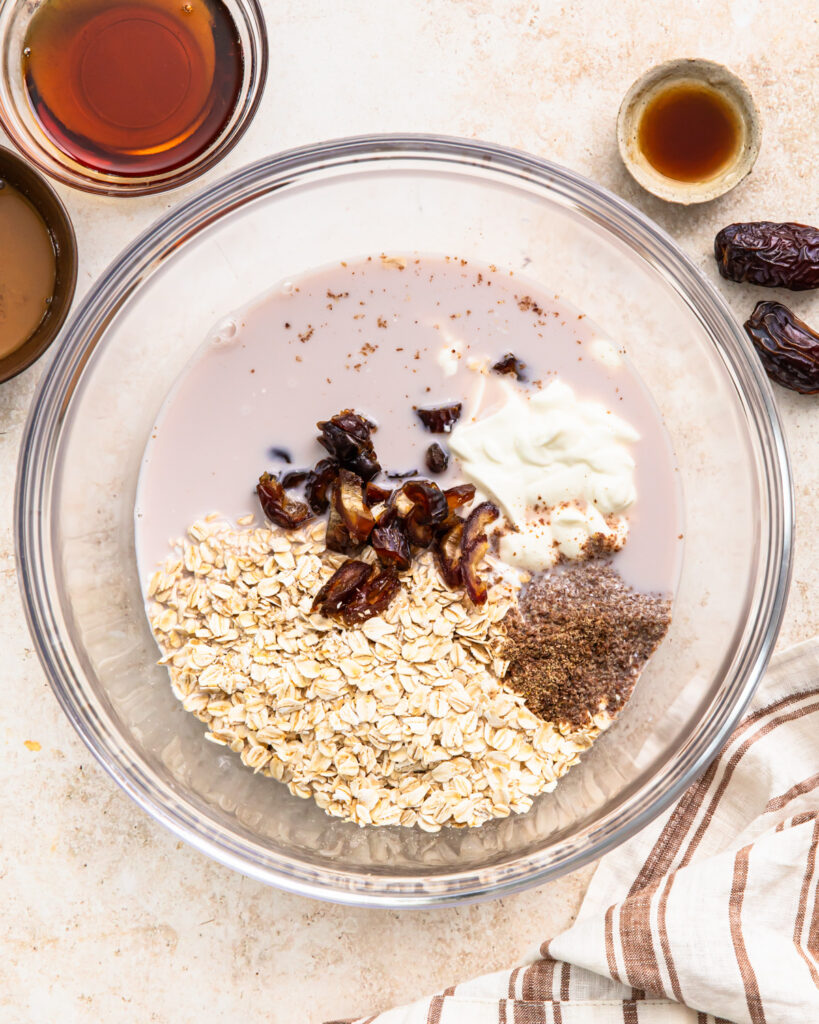Oats, dates, vanilla, flaxseed, Greek yogurt and almond milk in a bowl.